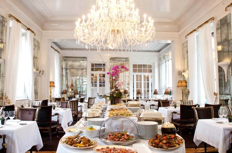 Sala da pranzo con grande lampadario a gocce di cristallo e tavolo buffet con vassoi di portate al centro.