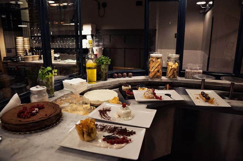 Bancone con piatti di dolci assortiti, torte intere e barattoli di vetro con biscotti.