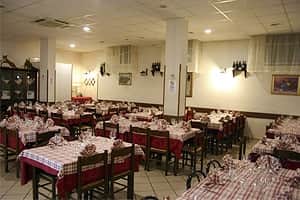 Sala da pranzo con tavoli apparecchiati con tovaglie a quadri rossi e bianchi e sedie scure.