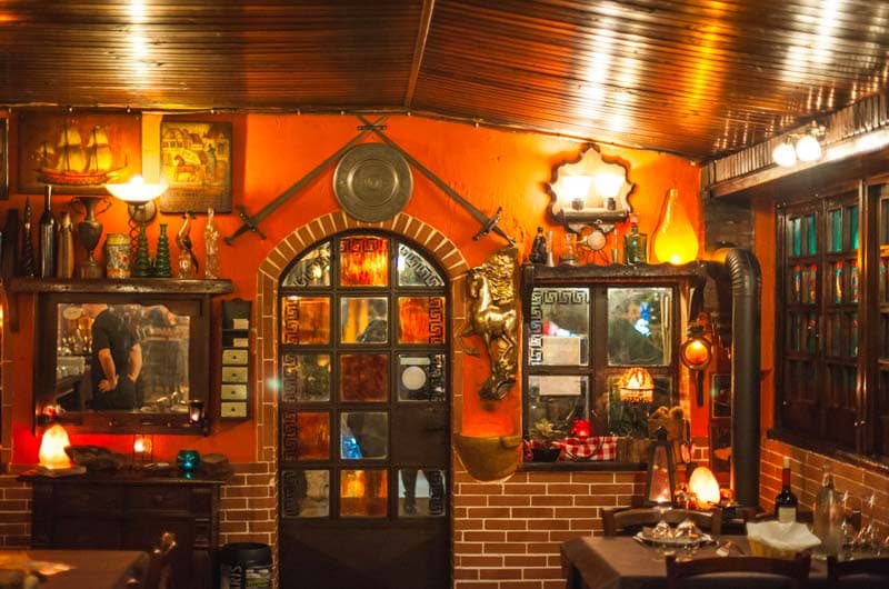 Sala interna con parete arancione, porta a vetri colorati, spade decorative e statua di cavallo dorato.