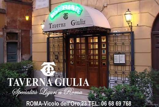Ingresso di un ristorante con tenda beige e insegna verde luminosa 'Ristorante Taverna Giulia' sopra la porta.